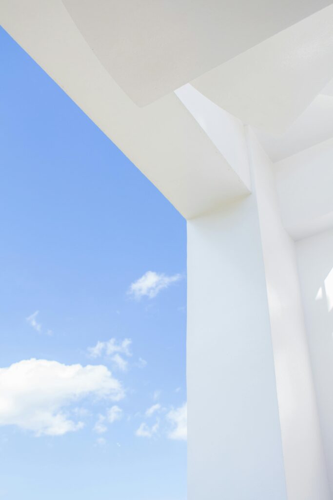 Sleek white structure with blue sky and clouds, showing minimalist architectural design elements.